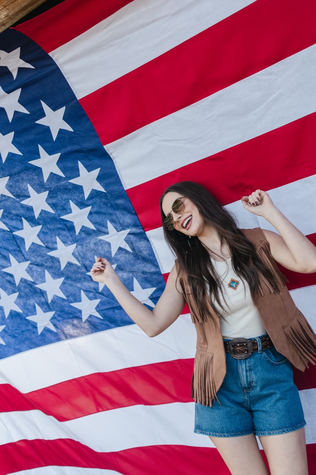 Demy Manosso dança de óculos de sol diante de uma grande bandeira dos Estados Unidos