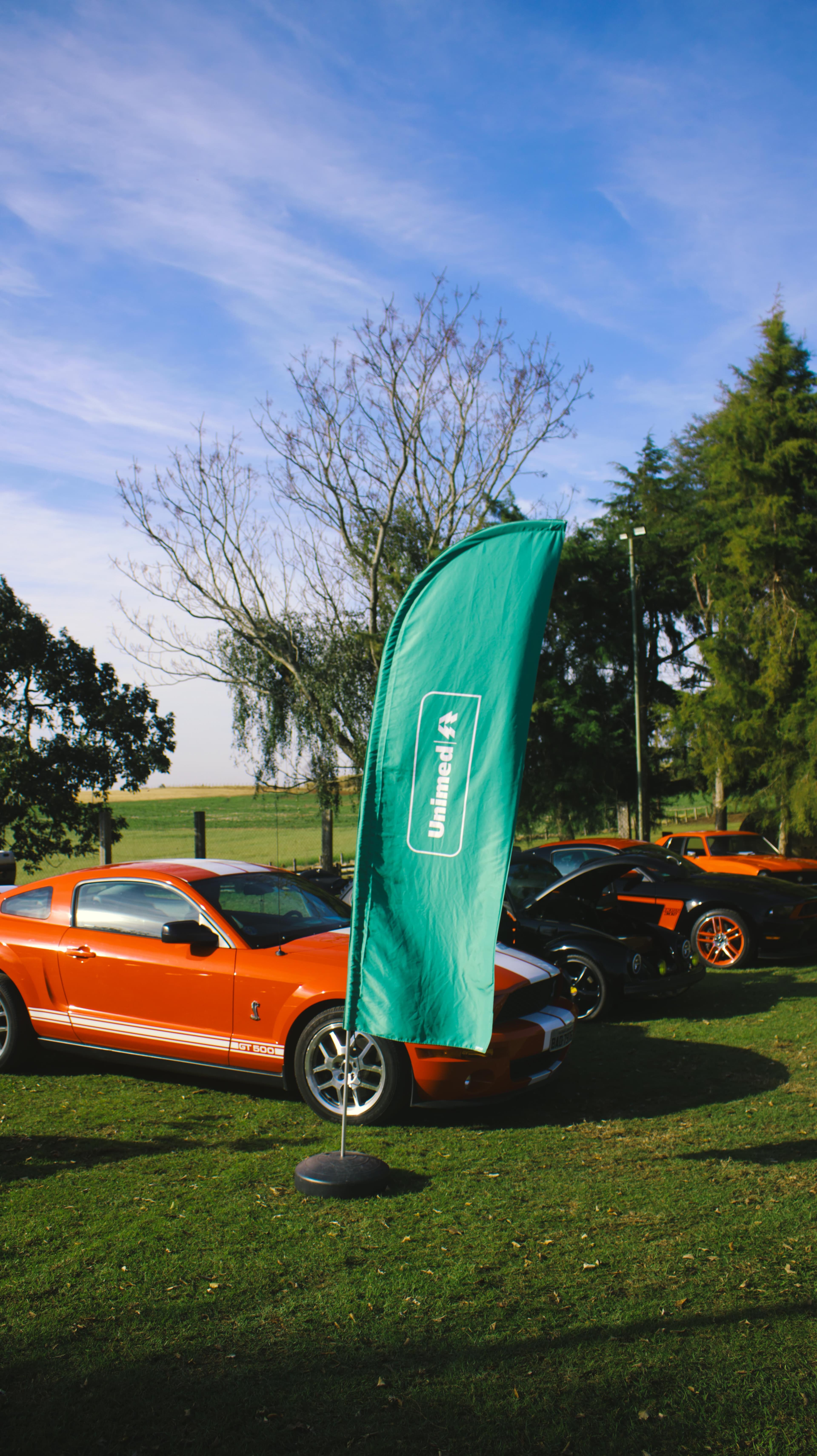 Bandeira da Unimed Ponta Grossa ao lado de um Mustang no Rock and Road 2025