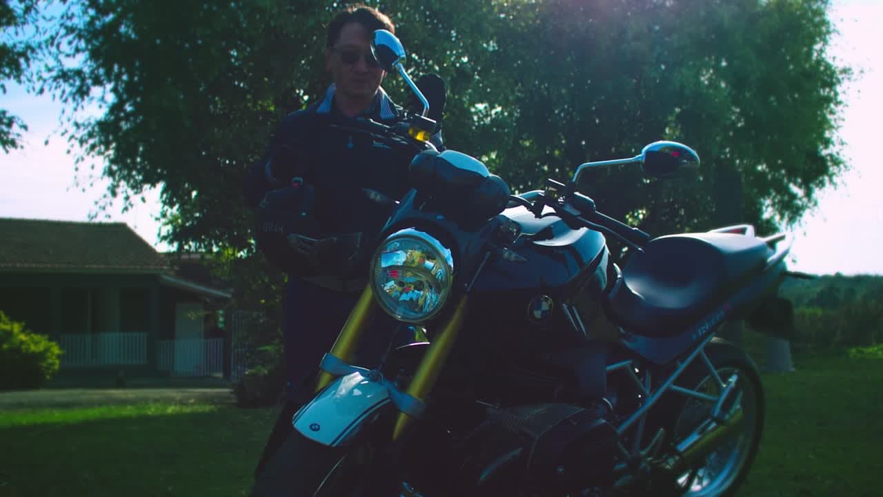 Cooperado ao lado de uma moto clássica em contraluz no Rock and Road 2025 da Unimed Ponta Grossa